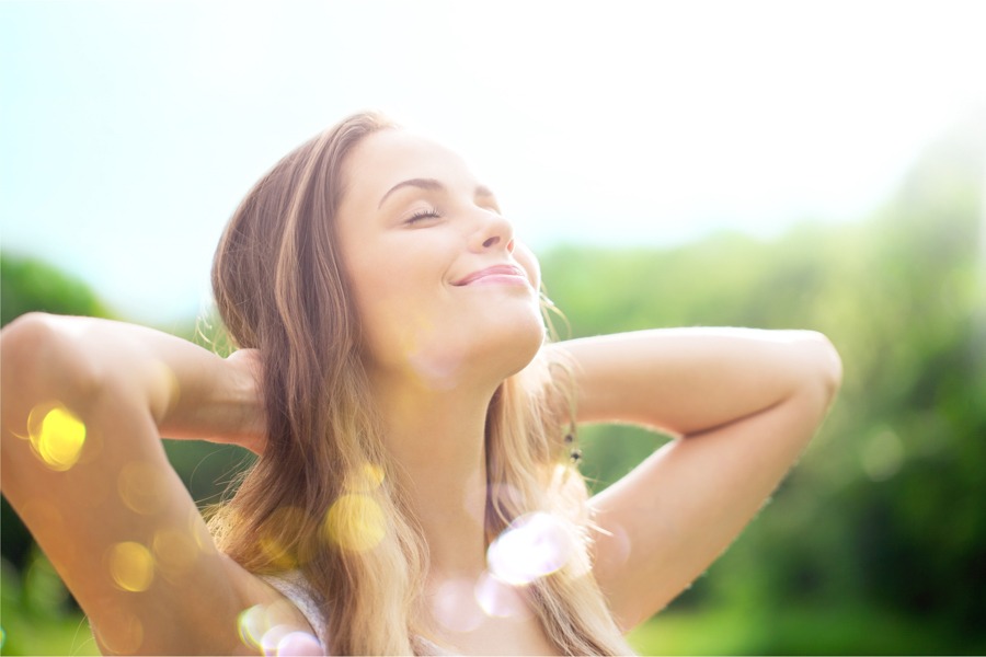 a woman smiles joyfully while gazing up at the sun, basking in its warm rays.