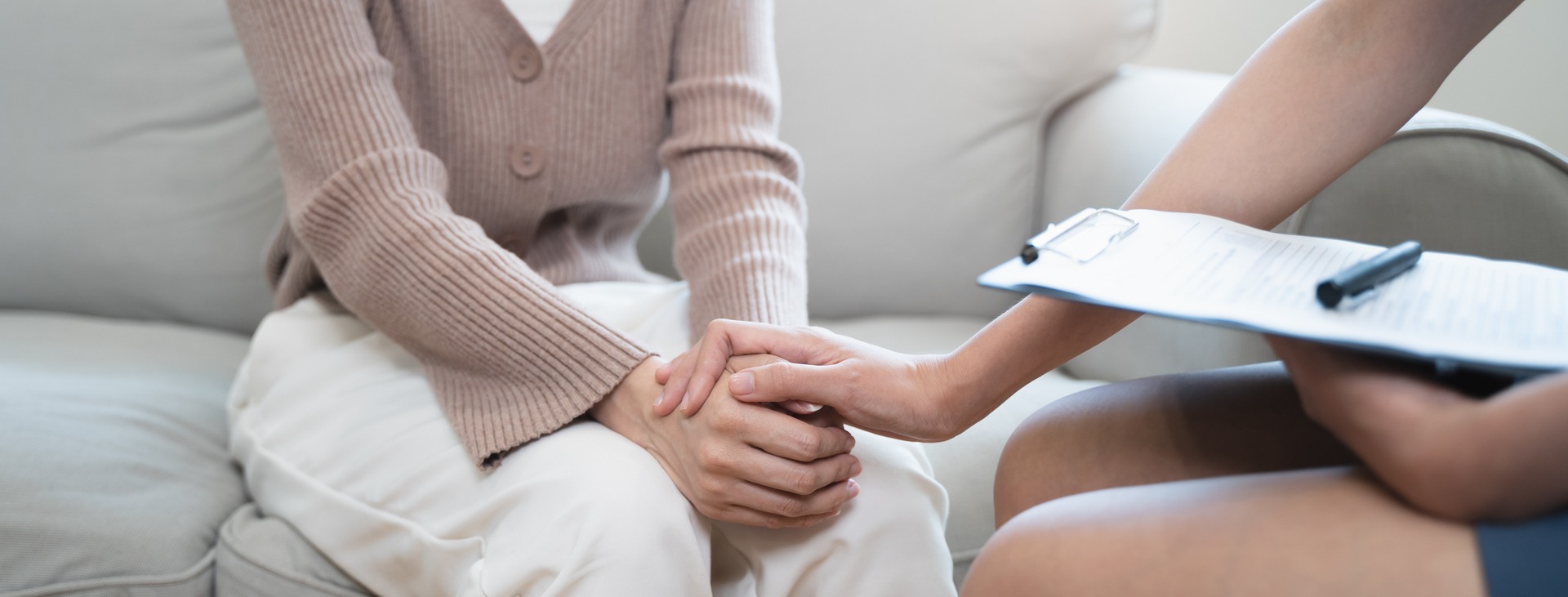 A woman and a doctor clasp hands, symbolizing support and trust in a medical setting.