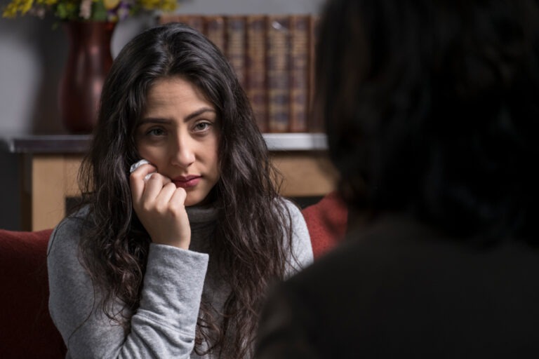 a woman with hands on cheeks talking to her therapist 