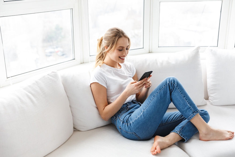 a woman sitting on couch while using her phone